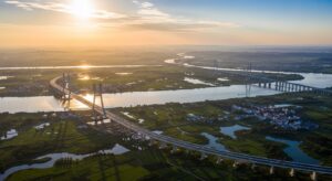 Aerial view of long suspension bridge over river floodplain landscape