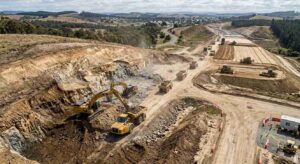 Aerial view of large-scale earthworks cut and fill operation with excavators and dump trucks at highway construction site