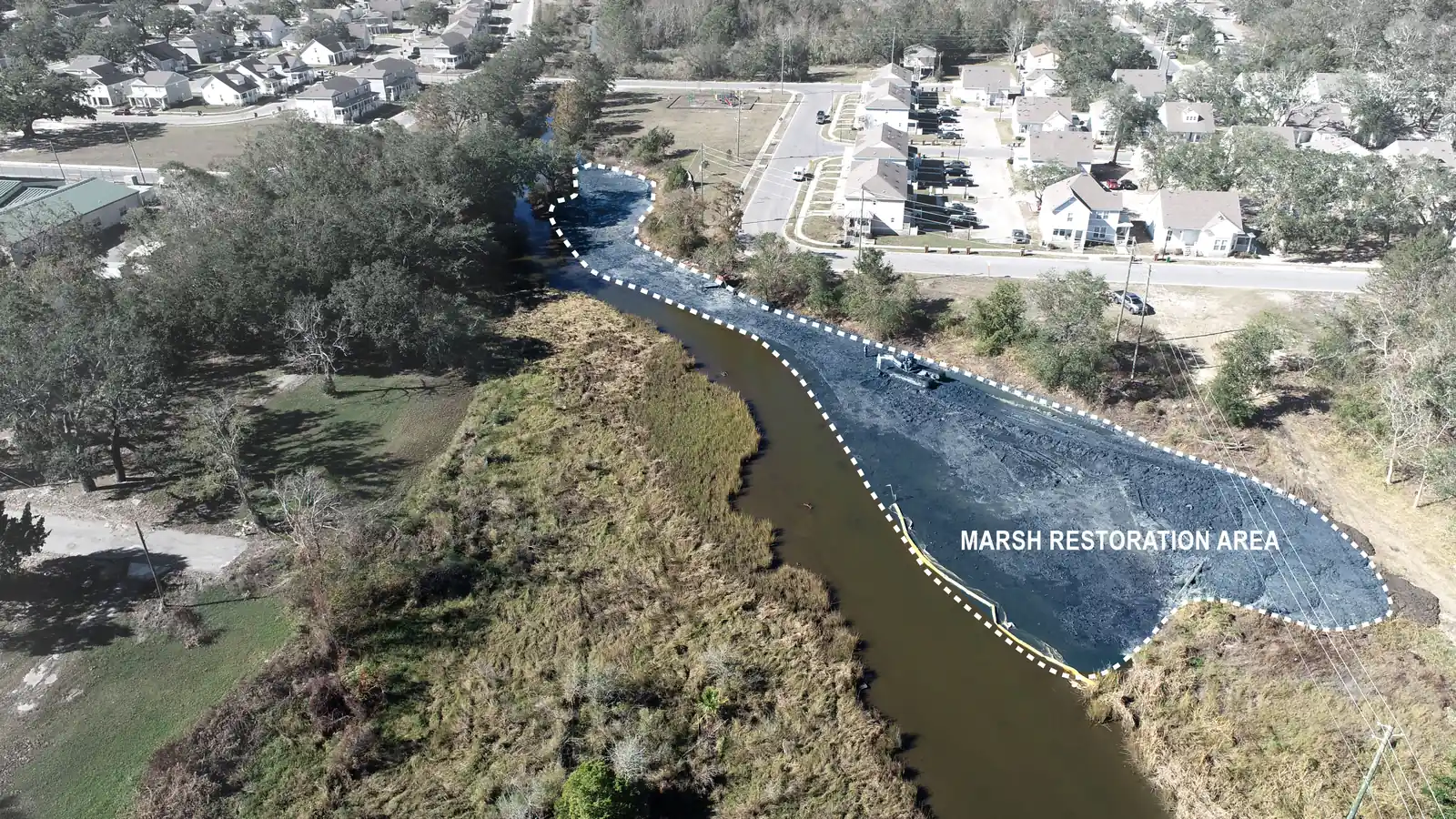 Annotated drone aerial of the Bayou Auguste marsh restoration area from the opposite end, with placed sediment, a piece of equipment and a turbidity curtain along the tidal channel